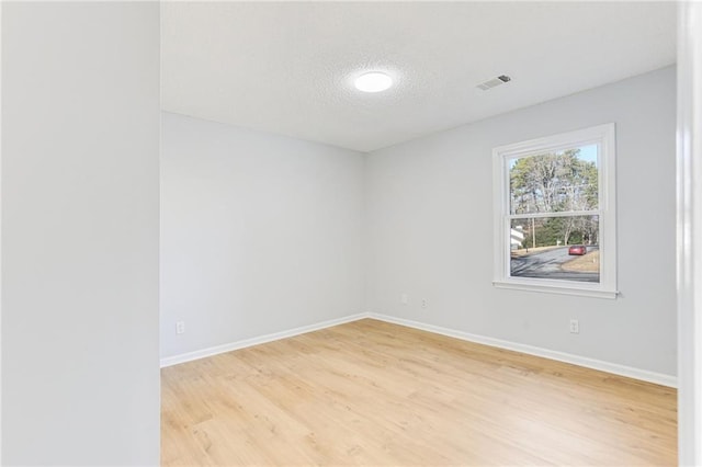 spare room featuring light hardwood / wood-style flooring and a textured ceiling