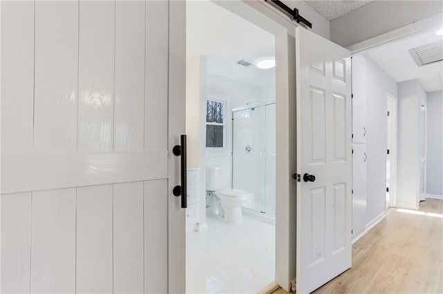 hallway featuring light hardwood / wood-style floors and a barn door