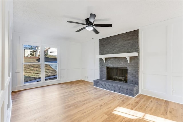 unfurnished living room featuring hardwood / wood-style flooring, ceiling fan, a fireplace, and a textured ceiling