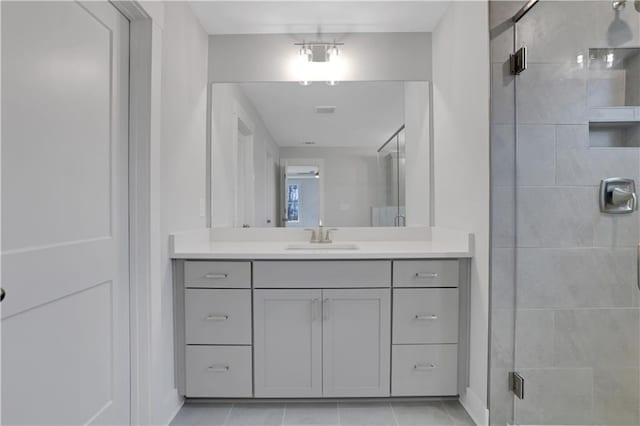 bathroom with tile patterned flooring, a shower with shower door, and vanity