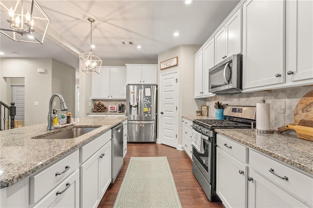 kitchen featuring pendant lighting, white cabinetry, sink, light stone counters, and stainless steel appliances