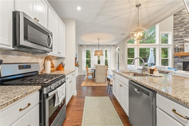 kitchen with white cabinetry, stainless steel appliances, decorative light fixtures, and sink