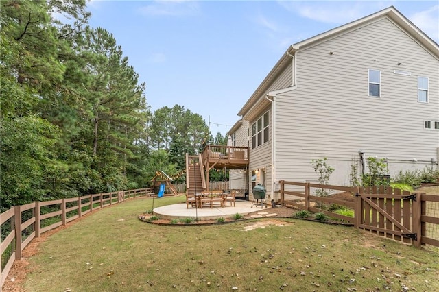 view of yard featuring a wooden deck, a patio area, and a playground