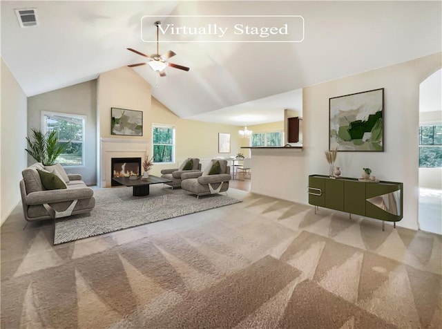 living room featuring vaulted ceiling, carpet floors, and ceiling fan with notable chandelier