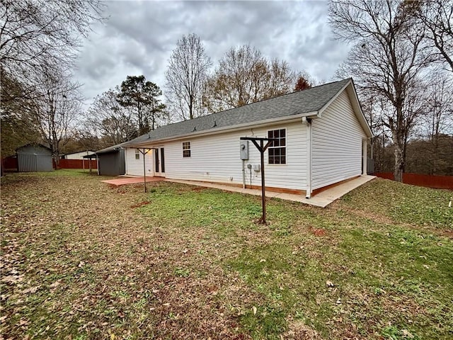 back of house with a storage shed, a yard, and a patio area