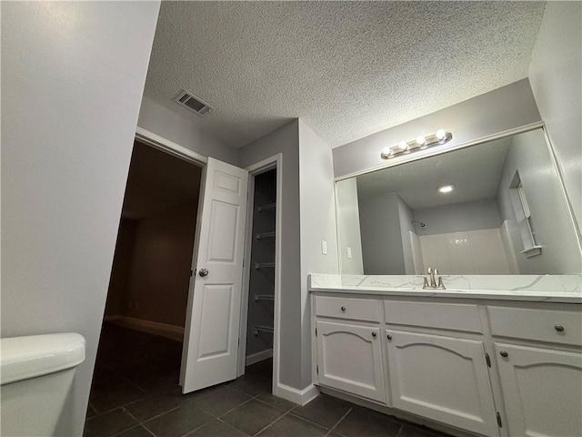 bathroom featuring a shower, tile patterned flooring, vanity, toilet, and a textured ceiling