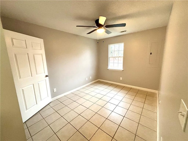 tiled spare room featuring a textured ceiling, electric panel, and ceiling fan