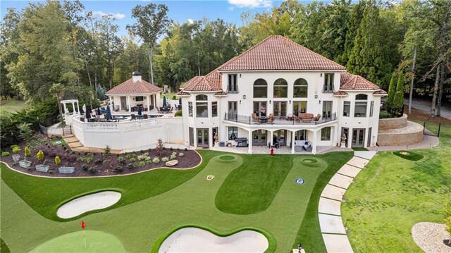 rear view of house featuring a balcony, a gazebo, a lawn, and a patio