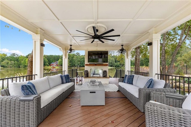 wooden terrace featuring ceiling fan, an outdoor hangout area, and a water view