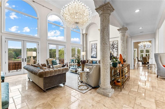 living room featuring ornate columns, plenty of natural light, french doors, and a towering ceiling