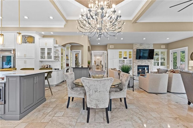 dining space with a notable chandelier, a fireplace, and crown molding