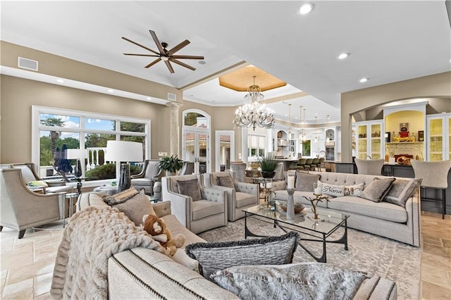 living room with ornamental molding, ceiling fan with notable chandelier, and decorative columns