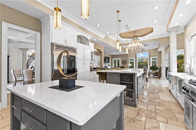 kitchen featuring gray cabinetry, ornate columns, high quality appliances, hanging light fixtures, and a large island