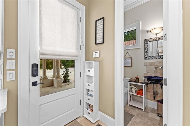 doorway to outside with ornamental molding and sink