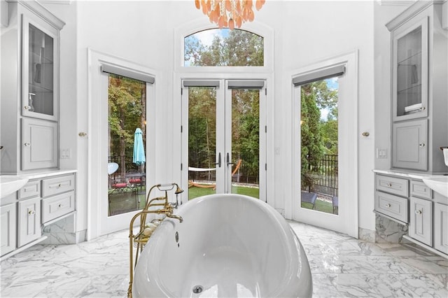 bathroom featuring vanity, a tub, french doors, a notable chandelier, and a towering ceiling