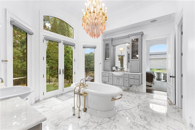 bathroom with french doors, a tub to relax in, vanity, and a healthy amount of sunlight