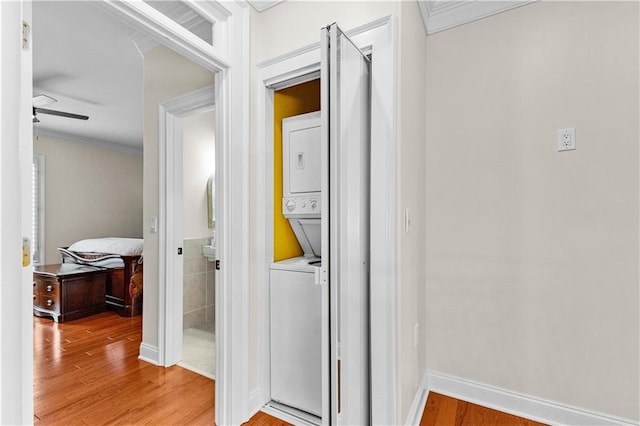 corridor featuring ornamental molding, hardwood / wood-style flooring, and stacked washing maching and dryer