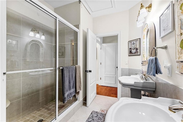 bathroom featuring a shower with door, tile patterned floors, and sink