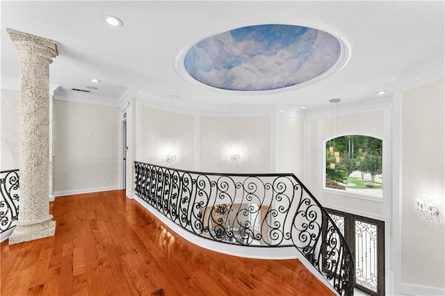 corridor with hardwood / wood-style flooring, crown molding, and decorative columns