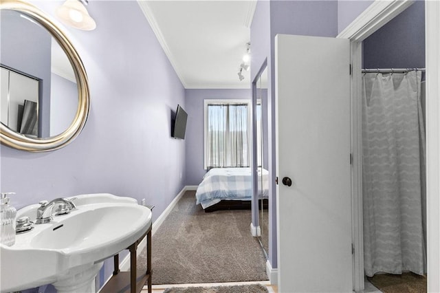 bathroom featuring walk in shower, crown molding, and sink