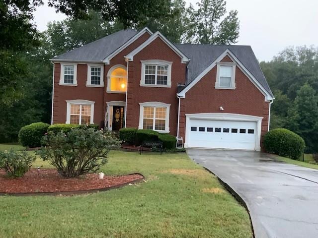 colonial inspired home with driveway, an attached garage, and a front yard