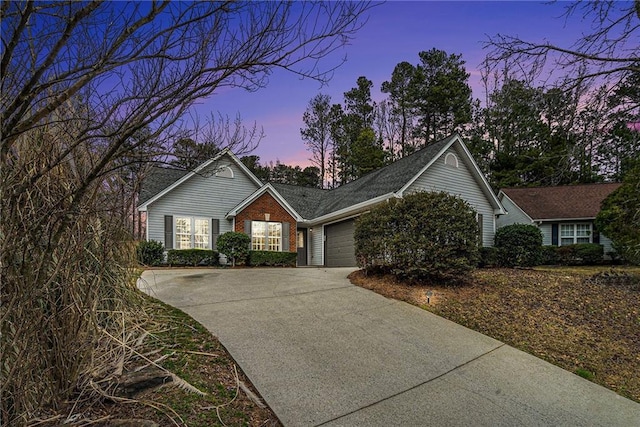 single story home featuring concrete driveway, brick siding, and an attached garage