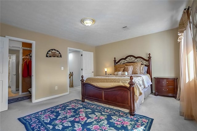 bedroom featuring a walk in closet and light colored carpet