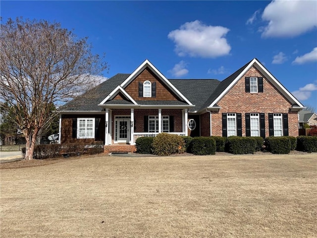 craftsman inspired home with a porch, brick siding, and a front lawn