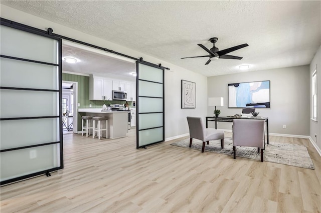 office featuring light wood finished floors, a textured ceiling, a barn door, and plenty of natural light