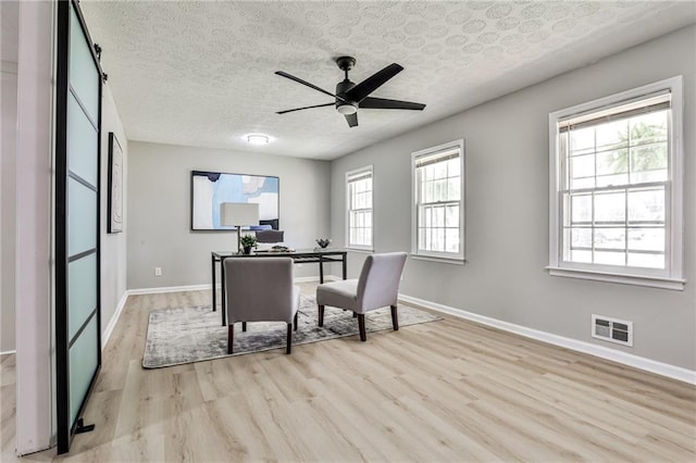 home office featuring visible vents, baseboards, a ceiling fan, and light wood-style floors