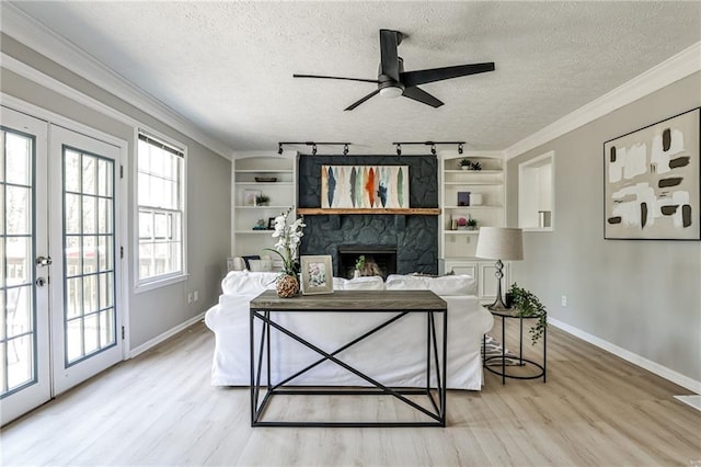 living area with baseboards, light wood-type flooring, ceiling fan, and a textured ceiling