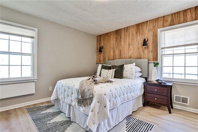 bedroom featuring a textured ceiling, visible vents, light wood-style floors, and baseboards