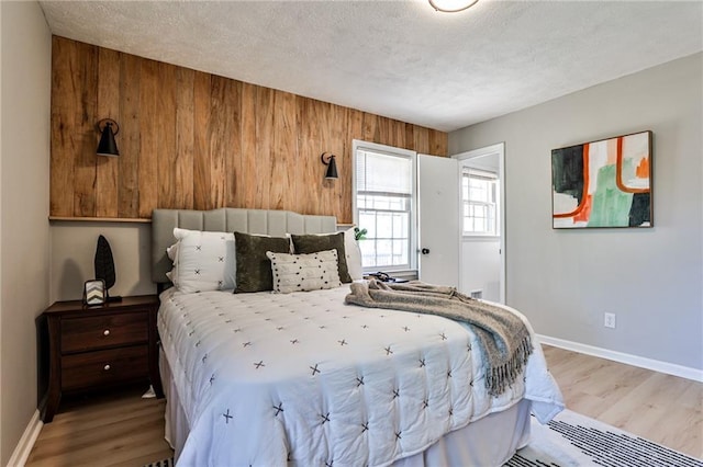 bedroom with baseboards, wood finished floors, and wooden walls