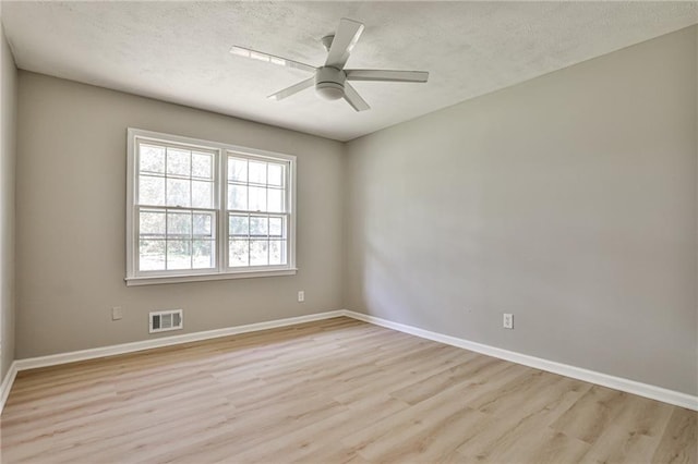 unfurnished room with a textured ceiling, light wood-style flooring, visible vents, ceiling fan, and baseboards