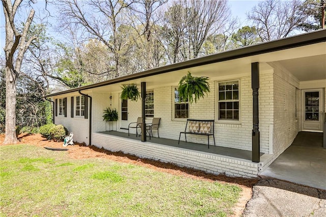 exterior space with a porch, a lawn, and brick siding