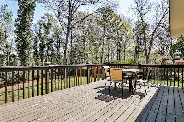 deck featuring outdoor dining area and a lawn