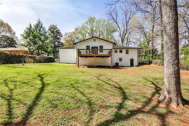 back of property featuring fence, a chimney, a yard, and a wooden deck