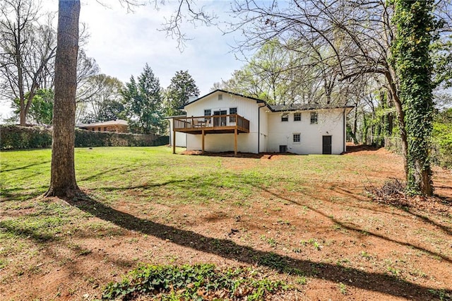 exterior space featuring fence, a wooden deck, and a lawn