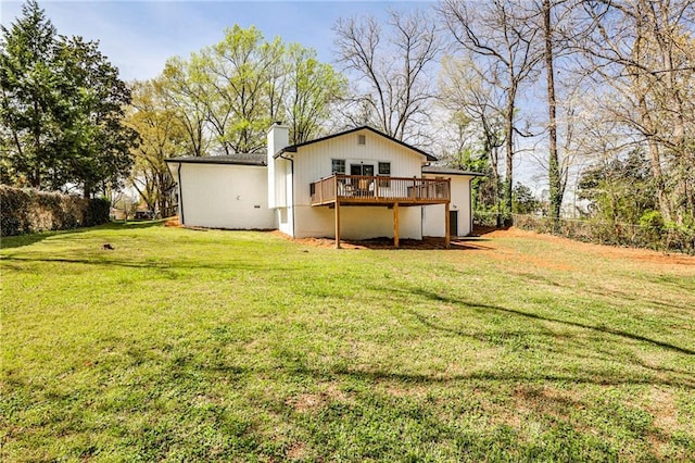 rear view of property with a lawn, fence, a chimney, and a deck