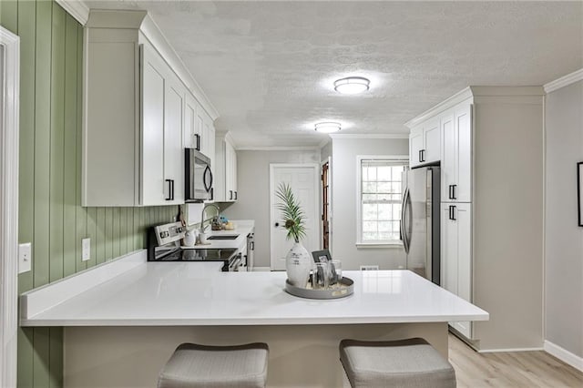 kitchen featuring ornamental molding, a kitchen breakfast bar, a peninsula, and appliances with stainless steel finishes