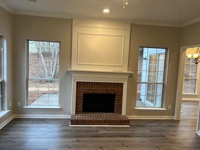 unfurnished living room with baseboards, wood finished floors, an inviting chandelier, crown molding, and a fireplace