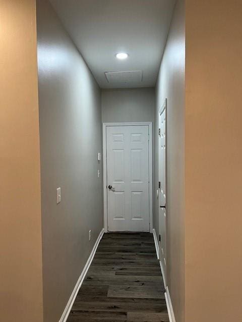 hall with dark wood-type flooring, visible vents, and baseboards