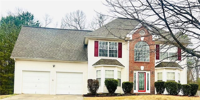 view of front facade with a garage, roof with shingles, and driveway