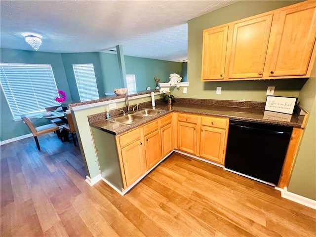 kitchen with a sink, light brown cabinets, a peninsula, and dishwasher