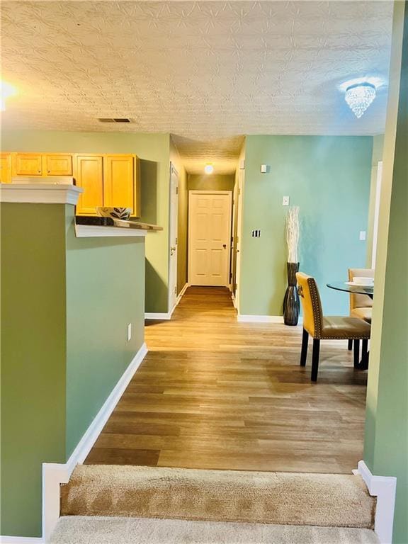 hallway with visible vents, stairway, light wood-style flooring, and baseboards