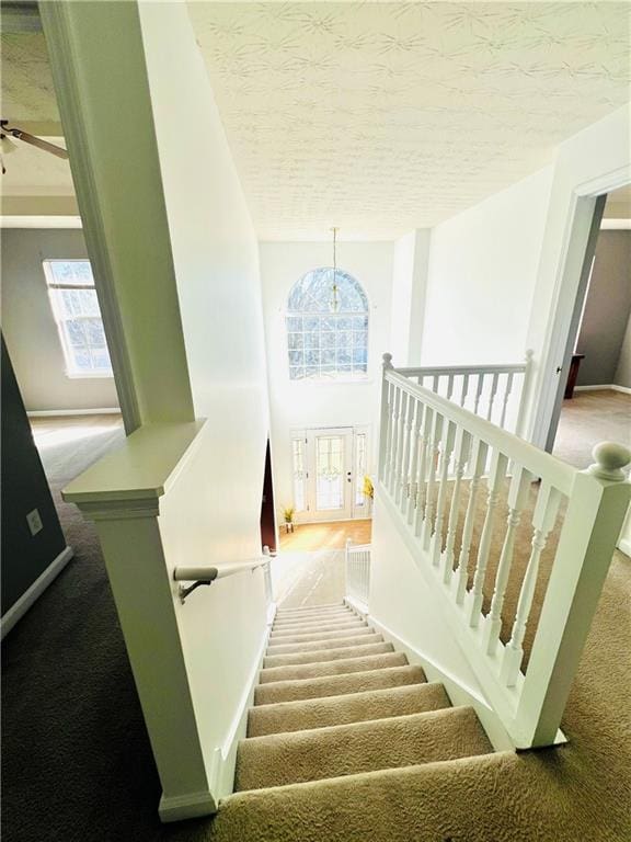 stairs with a textured ceiling and carpet