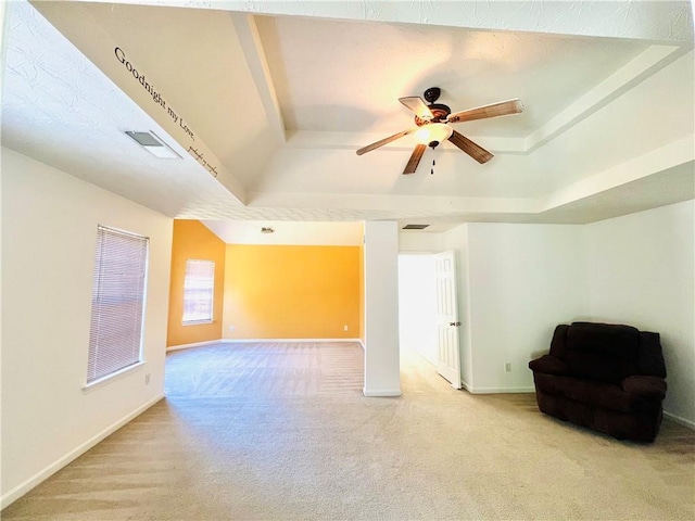 spare room with a tray ceiling, visible vents, light colored carpet, a ceiling fan, and baseboards