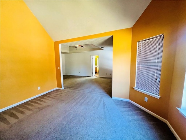 carpeted spare room featuring vaulted ceiling and baseboards