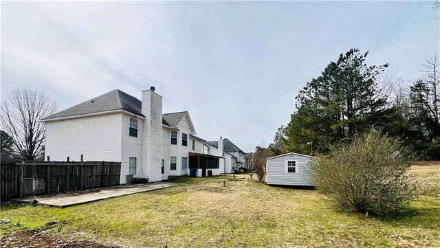 exterior space featuring an outbuilding, a patio area, fence, and a storage unit