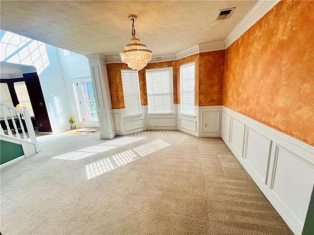 unfurnished room featuring a decorative wall, light carpet, visible vents, stairway, and decorative columns